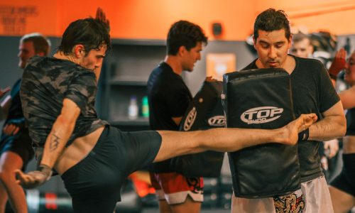 Lid van BBM Gym oefent kickbokstechnieken op pads tijdens groepsles in Maastricht